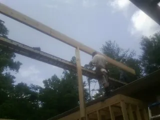 Carpenter setting a ridge beam over a new addition frame — Ice Dam Removal by Roofing Brothers in Rush Springs