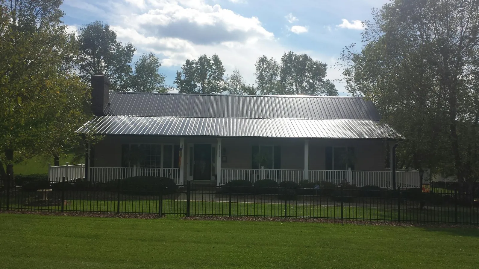 Gray metal roof on a brick ranch with a full width front porch — Gutter Guard Installation work by our crew in Rush Springs