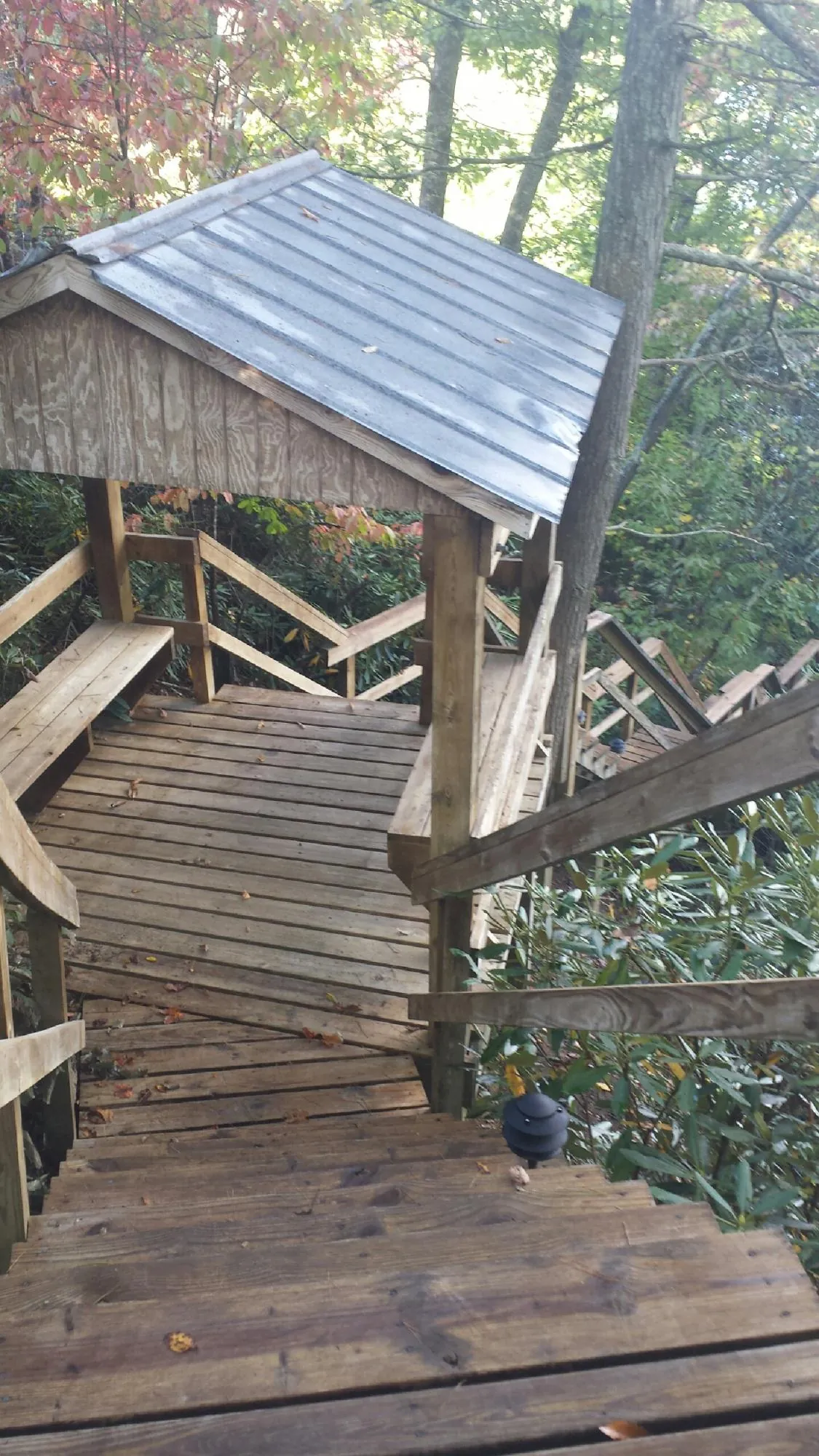 Metal roofed shelter over wooden steps on a wooded walkway — Skylight Repair & Installation work by our crew in Rush Springs