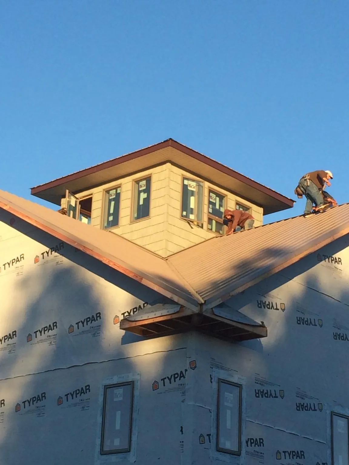 Roofers working around a rooftop cupola on a new metal roof at sunset — Roof Waterproofing in Rush Springs by Roofing Brothers